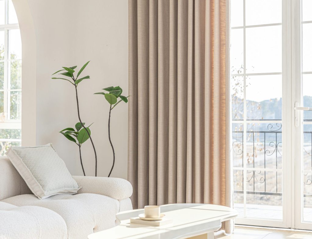 Un salon lumineux avec des rideaux aux tons neutres.